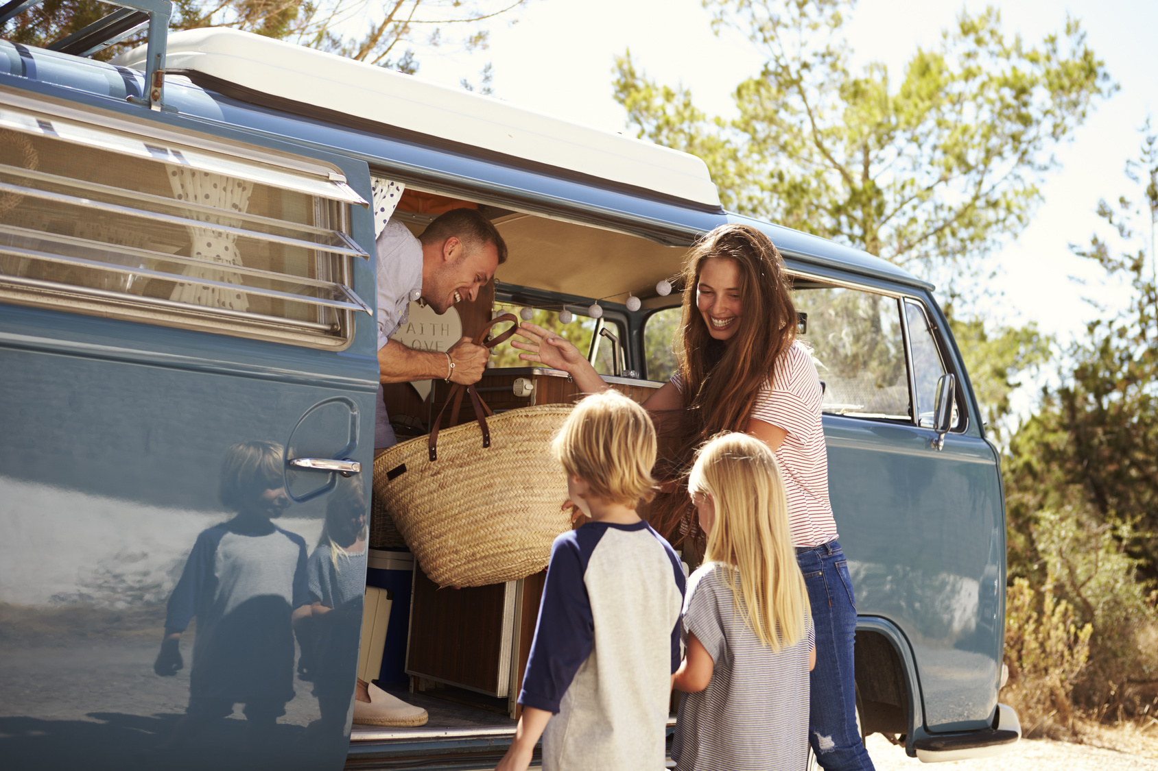 Family packing up their camper van for a road trip vacation